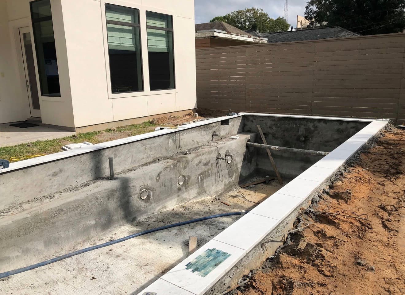 Pool under construction — bare gunite shell with coping and tile being installed — Houston, TX