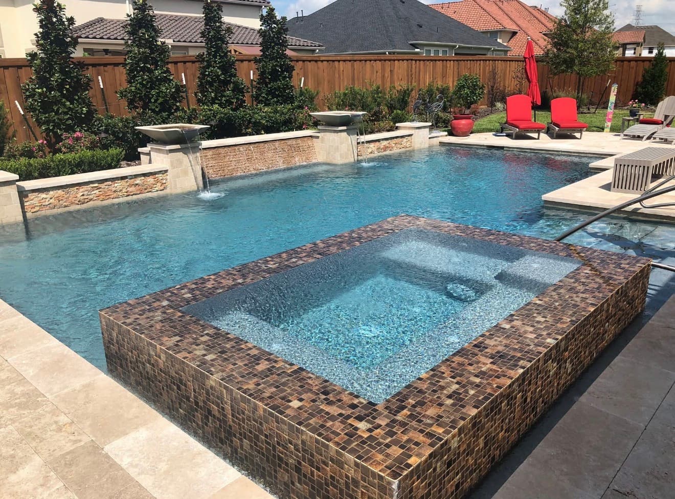 Custom pool with raised mosaic glass tile spa, dual water scuppers, and travertine deck — Houston, TX