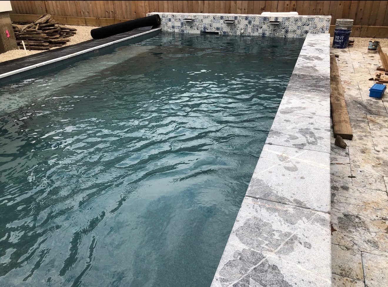 Close detail of an iridescent purple, blue and gold glass mosaic spillway band between spa and pool — Houston, TX