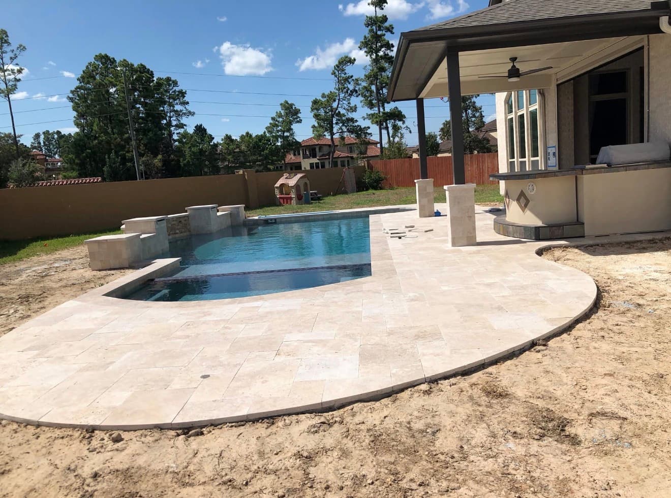 Pool and raised spa with a pebble interior finish, glass mosaic spillway and travertine coping — Houston, TX